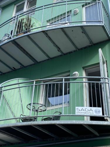 a green building with a balcony with a sign on it at Saga Apartments Akureyri in Akureyri