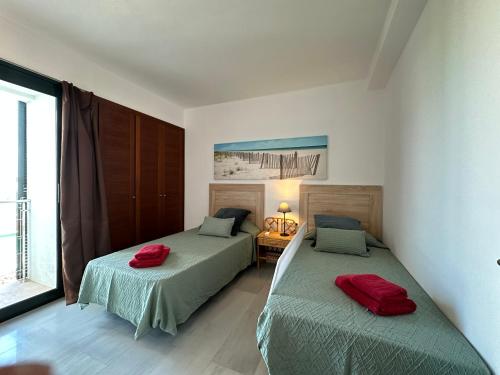 a bedroom with two beds with red pillows on them at MARINA 24 by SOM Menorca in Fornells