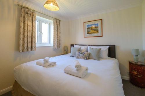 sypialnia z dużym białym łóżkiem z ręcznikami w obiekcie 9 The Coastguards w mieście Thorpeness