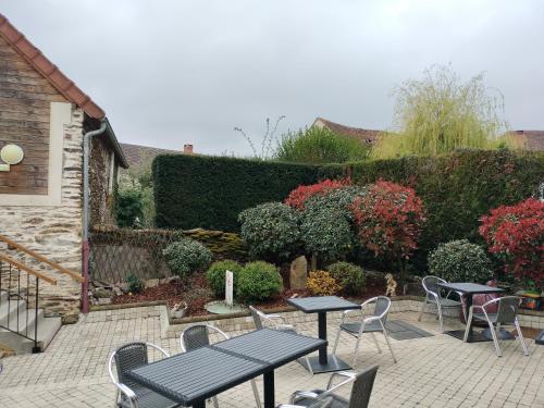 a patio with tables and chairs in a garden at Auberge des Colettes in Coutansouze