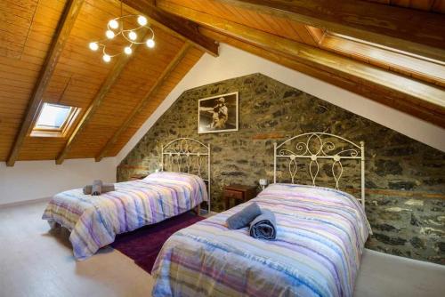 1 dormitorio con 2 camas y pared de piedra en Casitas centro panticosa, en Panticosa