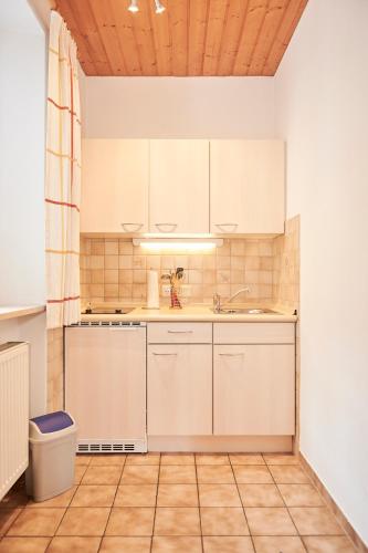 a kitchen with white cabinets and a wooden ceiling at Haus Ranker in Reit im Winkl