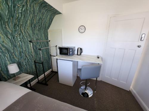 a room with a bed and a desk with a microwave at Solihull Shared House in Birmingham