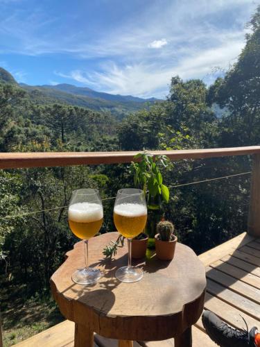 zwei Gläser Bier auf einem Holztisch auf einem Balkon in der Unterkunft Reserva Jacarandá Cabanas in Aiuruoca