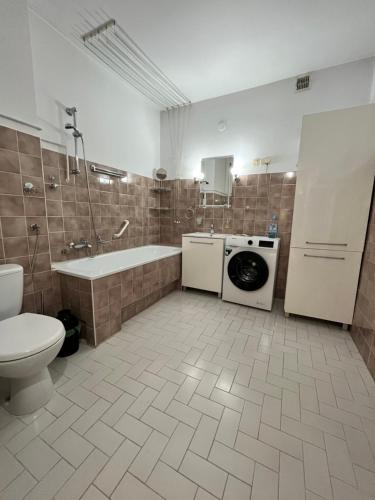 a bathroom with a tub sink and a washing machine at Apartament Wojska Polskiego 45 in Wadowice