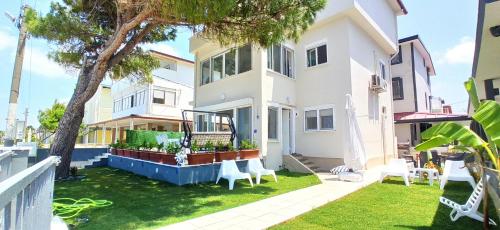 Biały dom z ogródkiem z drzewem w obiekcie Villa Plaj w mieście Kusadası