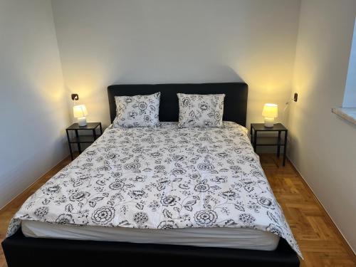 a bed with a black and white comforter and two lamps at Apartament Wojska Polskiego 45 in Wadowice