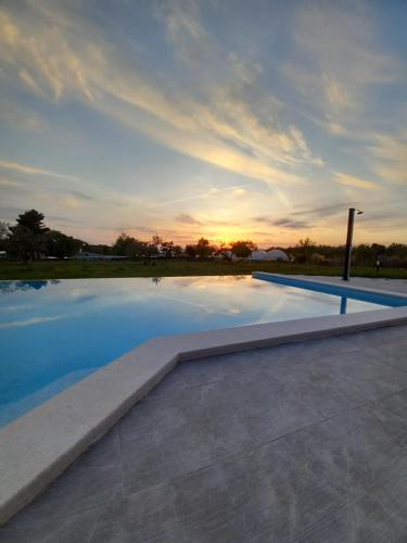 a swimming pool with a sunset in the background at Hotel Delfin Lanterna in Tar