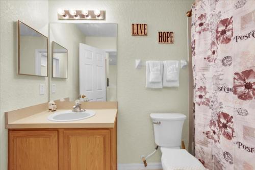 a bathroom with a sink and a toilet and a mirror at Regal Palms Lovely 3 Br Sleeps 8mins To Disney in Davenport