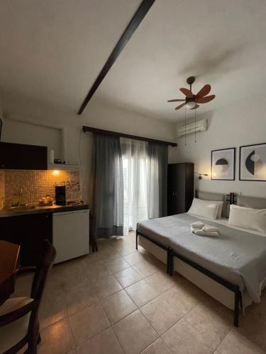 a bedroom with a bed and a kitchen and a ceiling fan at ΑΡΓΩ in Kala Nera