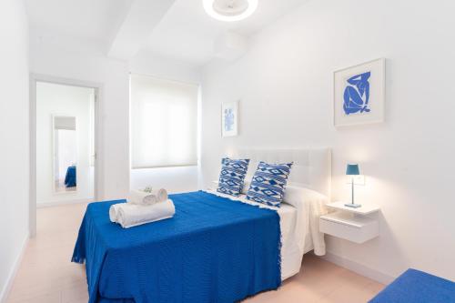 um quarto branco com uma cama com lençóis azuis em Expoholidays- Apartamento Federico García Lorca em Almeria
