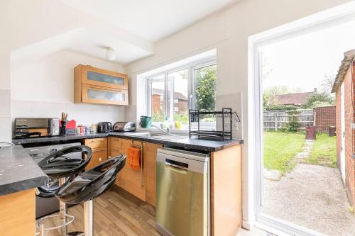 una cocina con encimera y algunas sillas. en Spacious 3-Bed House with car park near Heathrow, en Hounslow