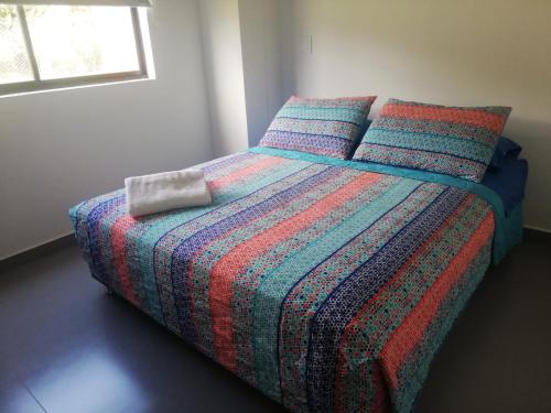 a bedroom with a bed with a colorful blanket and pillows at Casa Campestre Altamira in Los Curos