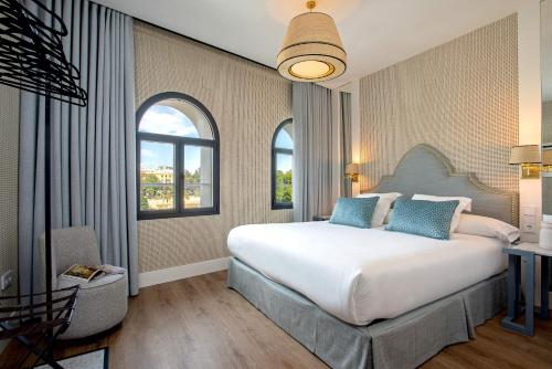 a bedroom with a large bed and two windows at Genteel Home Betis 67 in Seville