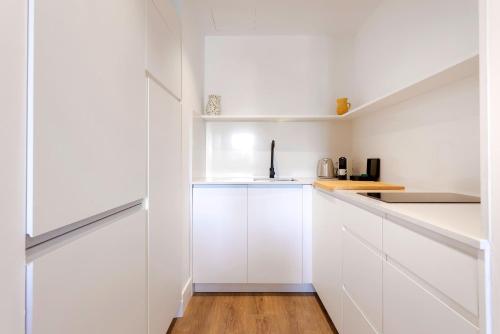 a white kitchen with white cabinets and a wooden floor at Genteel Home Betis 67 in Seville