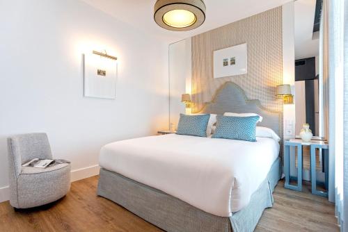a bedroom with a large white bed and a chair at Genteel Home Betis 67 in Seville