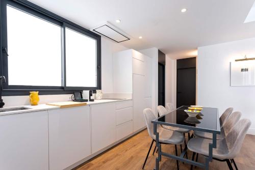 a kitchen with white cabinets and a black table and chairs at Genteel Home Betis 67 in Seville