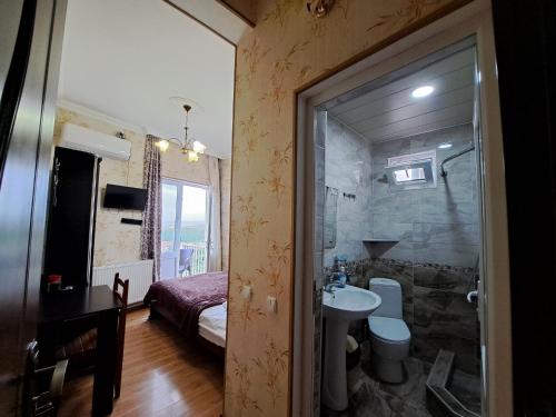 ein Bad mit einer Dusche, einem Waschbecken und einem Bett in der Unterkunft Guest House Maria in Sighnaghi