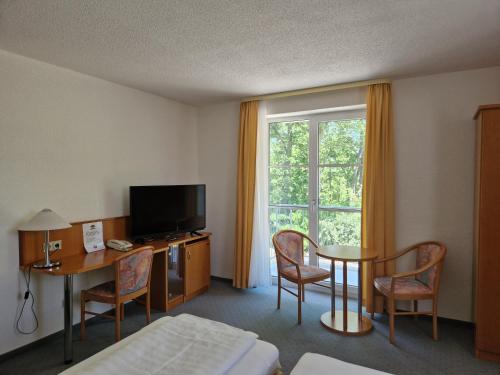 une chambre d'hôtel avec un lit, une table et une fenêtre dans l'établissement Hotel Siebeneichen, à Meissen