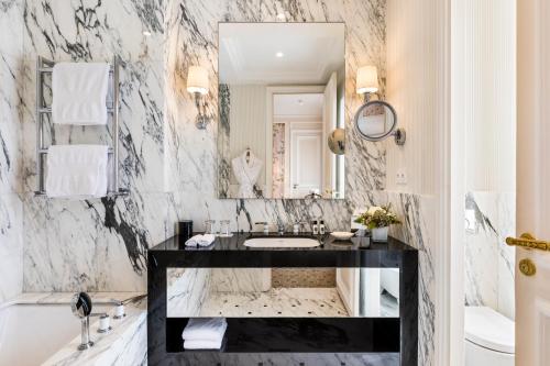 a marble bathroom with a sink and a mirror at Hôtel San Régis in Paris