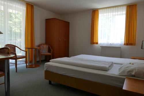 Schlafzimmer mit einem Bett, einem Tisch und einem Fenster in der Unterkunft Hotel Siebeneichen  in Meißen