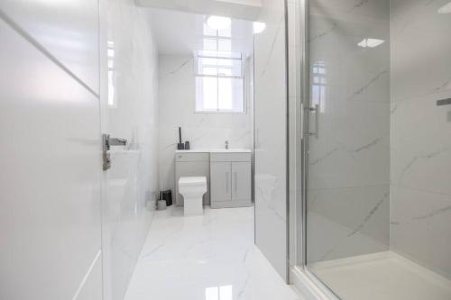 a white bathroom with a toilet and a shower at The Pocklington - The Guild Suite in Leicester
