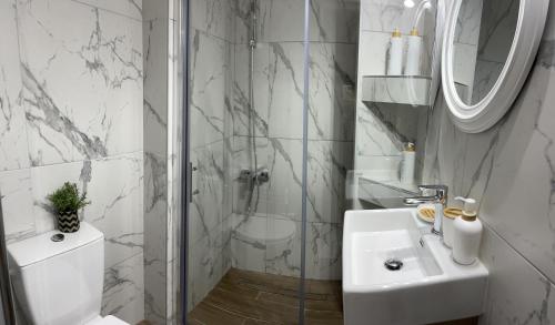 a white bathroom with a shower and a sink at Studio Coral by the sea in Neoi Epivates