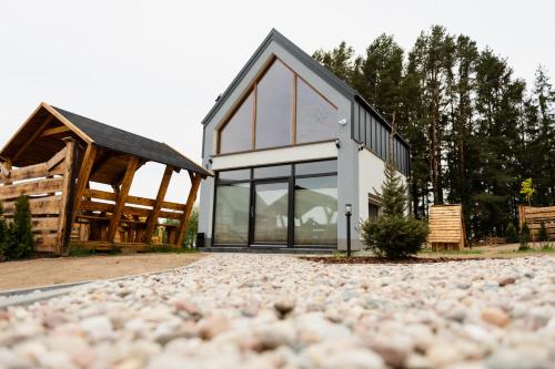 a house with glass windows and a gravel driveway at Bez Zegarka Osada nad Jeziorem Rospuda in Filipów
