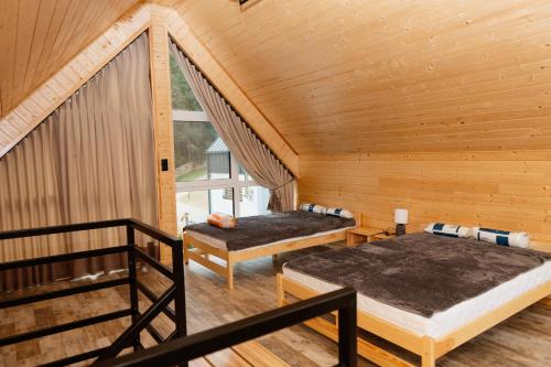 2 łóżka w pokoju z drewnianymi ścianami w obiekcie Bez Zegarka Osada nad Jeziorem Rospuda w mieście Filipów