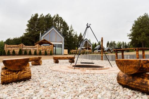 a playground with benches and a swing and a building at Bez Zegarka Osada nad Jeziorem Rospuda in Filipów