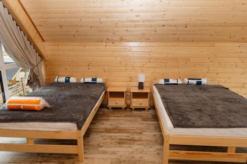 two beds in a room with wooden walls at Bez Zegarka Osada nad Jeziorem Rospuda in Filipów