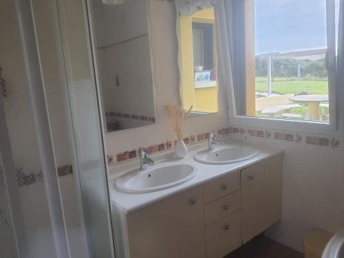 a bathroom with two sinks and a window at Maison du phare. in Plouarzel