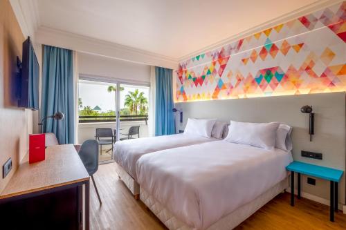 a hotel room with a large bed with a colorful ceiling at Allegro Agadir in Agadir