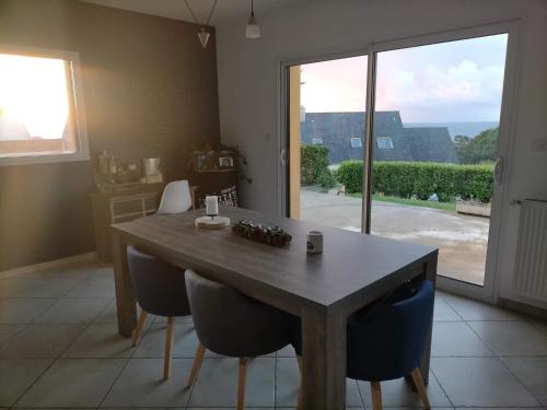 une table de salle à manger avec des chaises et une grande fenêtre dans l'établissement Maison du phare., à Plouarzel