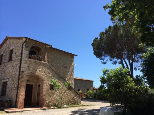 an old stone building with a tree in front of it at Villa Acquaviva Wine Resort in Montemerano