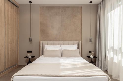 1 dormitorio con 1 cama blanca grande y 2 mesas en La Maison Suites en Zakynthos