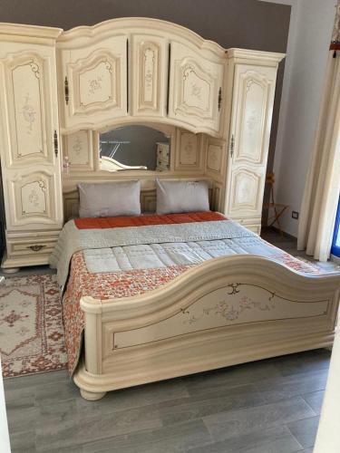 ein großes Bett mit einem großen Kopfteil aus Holz in der Unterkunft Appartement Djerba in El Mây