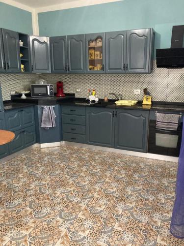 a kitchen with blue cabinets and a tile floor at Appartement Djerba in El Mây