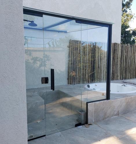 a glass shower with a tub in a bathroom at Statera Host in Alto Paraíso de Goiás