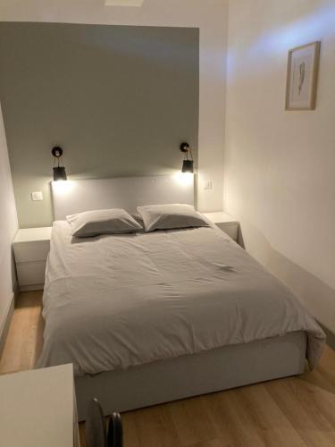 une chambre avec un grand lit blanc avec deux lumières dans l'établissement T3 central et paisible à Annecy, à Annecy