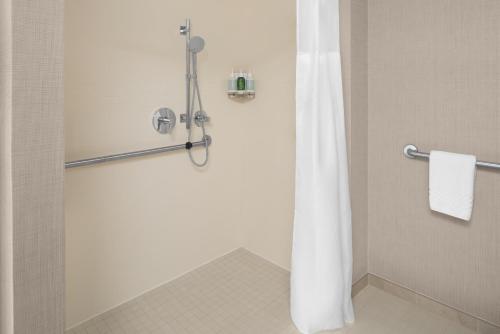 La salle de bains est pourvue d'une douche avec un rideau de douche blanc. dans l'établissement Residence Inn Long Island Holtsville, à Holtsville