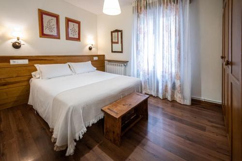 a bedroom with a white bed and a wooden floor at Apartamentos Casa Pichuana in Benasque