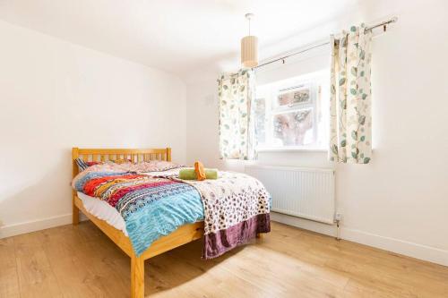 a bedroom with a bed and a window at Spacious 3BHK near Heathrow in Cranford