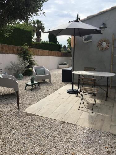a patio with a table and an umbrella and chairs at Carpédiem in Sanary-sur-Mer