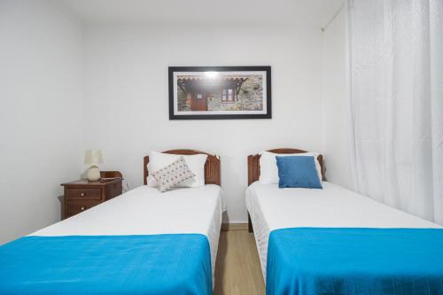 duas camas num quarto com branco e azul em Guest House Ribeirinho - Alojamento local em Miranda do Corvo