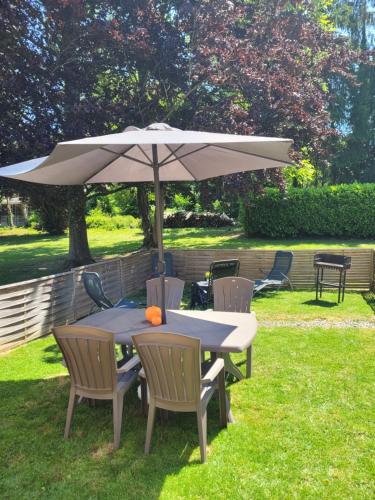 a table and chairs under an umbrella in the grass at Au chant des oiseaux in Rochefort