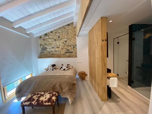 a bedroom with a bed and a stone wall at APARTAMENTOS KERCUS in Sevares