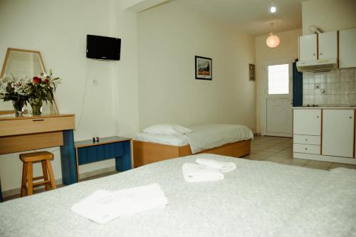 a room with two beds and a desk and a sink at Assa Inn in Pyrgadikia