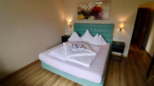 a bedroom with a white bed with a blue headboard at Hotel Residence MaVie in Lagundo