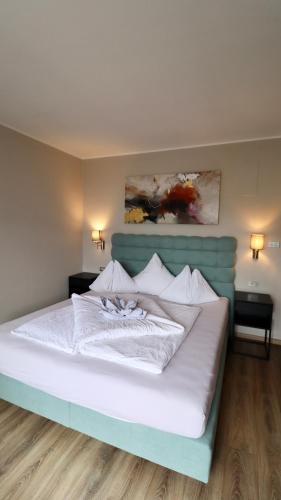 a bedroom with a white bed with a blue headboard at Hotel Residence MaVie in Lagundo